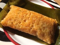 a piece of food sitting on top of a white and red plate next to a green leaf