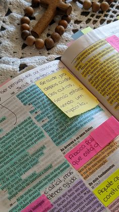 an open bible with sticky notes on it and a wooden cross in the back ground