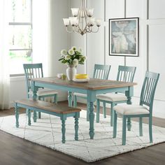 a dining room table with four chairs and a bench in front of a window on top of a rug