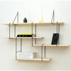 three shelves with books and other items on them against a white wall, one has a candle