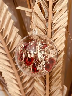 a glass ornament hanging from a palm tree filled with red and white beads