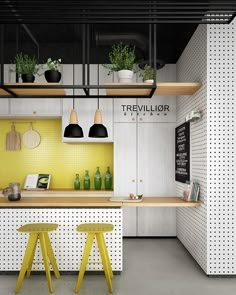 two yellow stools sit in front of a counter with bottles on it and plants hanging from the ceiling