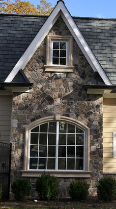 a stone house with white windows and black roof