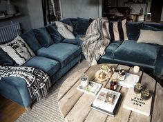 a living room with blue couches and pillows on the coffee table in front of it