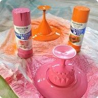 some spray paint and other items sitting on a piece of pink tissue paper next to an orange candle holder