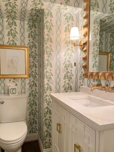 a white toilet sitting under a bathroom mirror next to a sink and a wooden floor