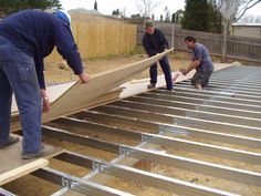 three men are working on the roof of a house that is being built with metal sheets