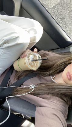 a woman sitting in the back seat of a car drinking from a cup