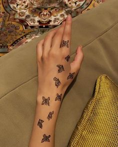 a woman's hand with tattoos on her left arm and butterfly tattoo on the right wrist