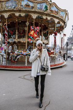 a woman standing in front of a merry go round with her hand on her hip