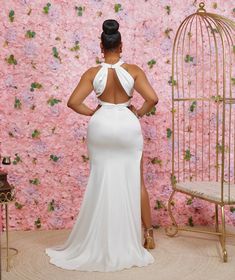 a woman standing in front of a wall with pink flowers and a birdcage