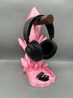 a pair of headphones sitting on top of a pink flower shaped stand with a cell phone in it