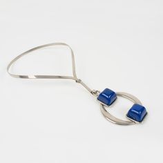 This is part of Chairish’s Costume Jewelry assortment.  Stylish Mid Century Modern Space Age collar necklace with a geometric pendant. A stainless steel rigid neckband and a pendant ornate with dimensional cobalt blue resin cabochons. No visible maker's mark. Measurements: neckband circumference is 15.38 in (39 cm) - pendant is 3.38 in long (8.5 cm) x 2.38 in wide (6 cm).  Please see the measurements noted above in the description for the best approximate dimensions. Modern Blue Pendant Jewelry, Modern Adjustable Cabochon Jewelry, Modern Blue Necklace With Polished Finish, Modern Blue Necklaces With Polished Finish, Modern Blue Necklace, Modernist Blue Jewelry With Polished Finish, Blue Modernist Jewelry With Polished Finish, Modernist Metal Jewelry With Large Pendant, Modern Blue Metal Necklaces