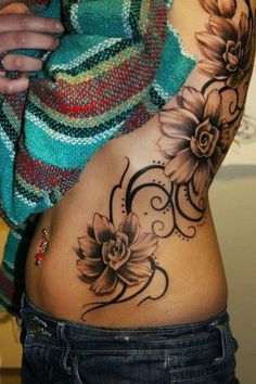 a woman's stomach with tattoos on it and flowers in the middle of her belly