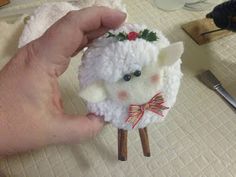 a hand is holding a small white sheep ornament