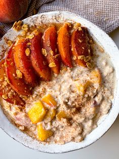 a bowl of oatmeal with peaches and granola on the side