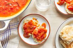 three plates with food on them next to a bowl of soup and a glass of water