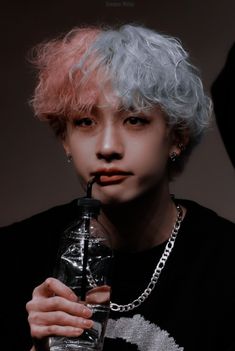 a person with grey hair holding a water bottle in their hand and wearing a chain around his neck