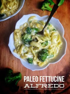 a plate of pasta with broccoli and cheese on it next to two bowls