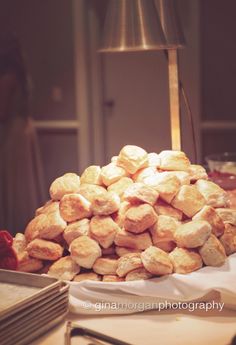 a pile of bread sitting on top of a table next to a lamp and plates