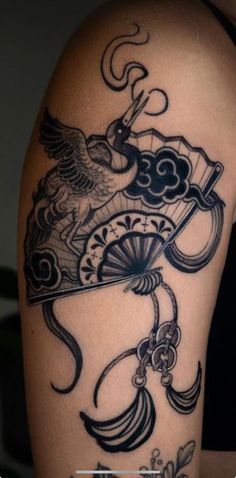 the back of a woman's arm with tattoos on it and an eagle holding a fan