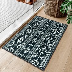 a black and white rug sitting on top of a wooden floor next to a potted plant