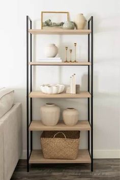 a shelf with vases and other items on it in a living room next to a couch