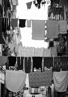 clothes hanging in an alley way with buildings in the backgrouds and laundry lines above them