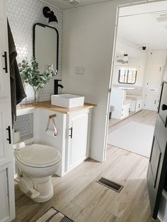 a white toilet sitting in a bathroom next to a wooden counter top under a mirror