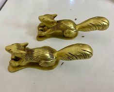 two gold colored metal animals sitting on top of a white counter next to each other