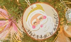 a christmas ornament hanging from a tree with ornaments around it and the words merry santa on it