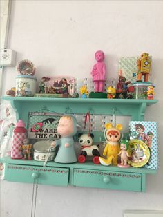 there is a shelf with many toys on it and other things in the shelves above