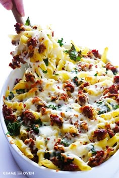 a person is scooping some food out of a casserole dish with meat and cheese