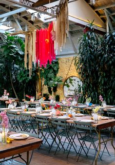 an indoor dining area with tables, chairs and hanging decorations on the ceiling in front of potted plants