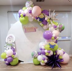 the balloon arch is decorated with purple, green and white balloons