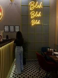 a woman standing in front of a bar with neon signs on the wall behind her