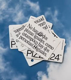 four white tags with black words on them against a blue sky and some clouds in the background