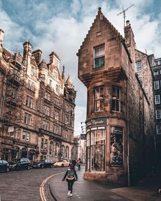 a woman is walking down the street in front of some old buildings on a cloudy day