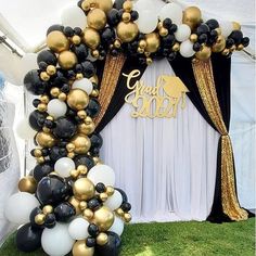 the balloon arch is decorated with black, white and gold balloons