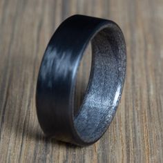 a wooden ring with black wood inlays sits on top of a wooden surface