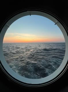 the sun is setting over the ocean as seen through a porthole in a ship