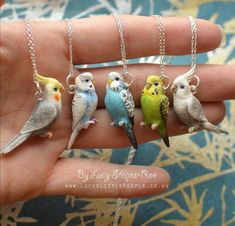 four small birds sitting on top of a person's hand with chains around them