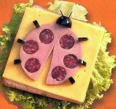 a ladybug sandwich made out of cheese and meat on a piece of bread