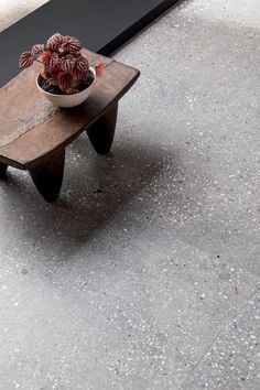 a small wooden table with a potted plant on it and a black bench in the background