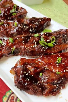 two pieces of meat on a plate with sesame seeds