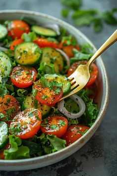 a salad with cucumbers, tomatoes, onions and herbs in a white bowl