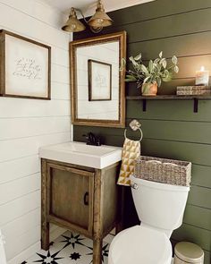 a white toilet sitting next to a sink in a bathroom under two framed pictures on the wall