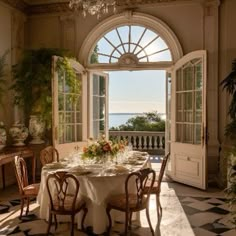 a dining room with a table and chairs in front of an open door leading to the ocean