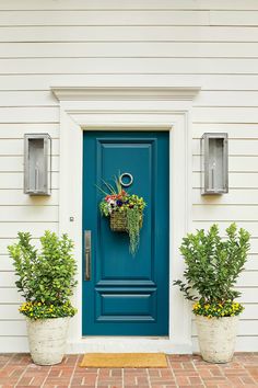 a blue front door with two planters on it