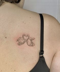 a woman's back with two swans tattoo on her left shoulder and right arm